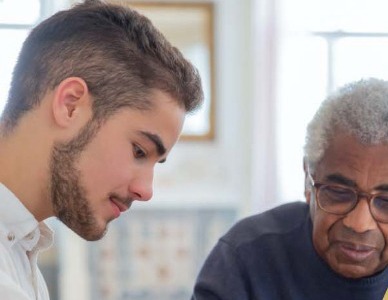 Young carer supporting an older man with his medication
